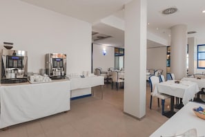 Hotellin ruokailutila, jossa on tarjolla buffet, sekä kahviautomaatteja ja monipuolinen valikoima erilaisia ruokia.