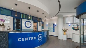 A hotel reception area with a blue counter, a map on the wall, and a potted plant. - CENTRO HOTEL - MARCON (Marcon)