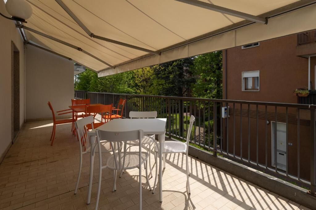 An outdoor patio with a table and chairs, a covered area, and a view of a building and trees.