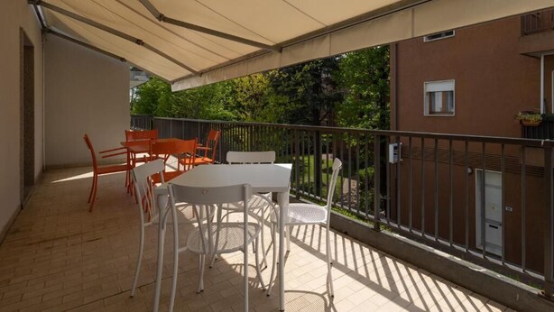 An outdoor patio with a table and chairs, a covered area, and a view of a building and trees. - CENTRO HOTEL - MARCON (Marcon)