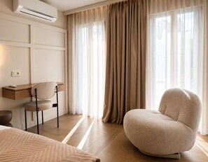 Ein modernes Schlafzimmer mit Bett, Schreibtisch, Stuhl und einem großen Fenster mit Vorhängen.