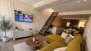 A modern living room with a sofa, coffee table, and a TV mounted on the wall. - Meros Marotti | Spacious 3BR Home in Zakynthos (Zakinthos)
