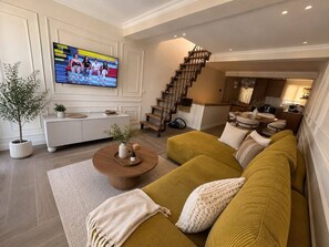 Ein modernes Wohnzimmer mit Sofa, Couchtisch und Wandfernseher.