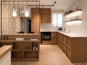 Eine moderne Küche mit Holzausstattung, einem Einbauofen, einer Mikrowelle und einer weißen Arbeitsplatte.