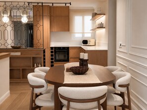 Eine moderne Küche mit Holzausstattung, einem Einbauofen, einer Mikrowelle und einem Essbereich mit rundem Tisch und sechs Stühlen.