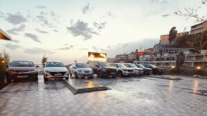 A parking area with multiple cars and a large billboard in the background. - The Palm Aryan Mussoorie 5min Mall Road (Mussoorie)