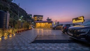 A hotel entrance with a paved driveway, parked cars, and a sign for 'Palmyan.' - The Palm Aryan Mussoorie 5min Mall Road (Mussoorie)