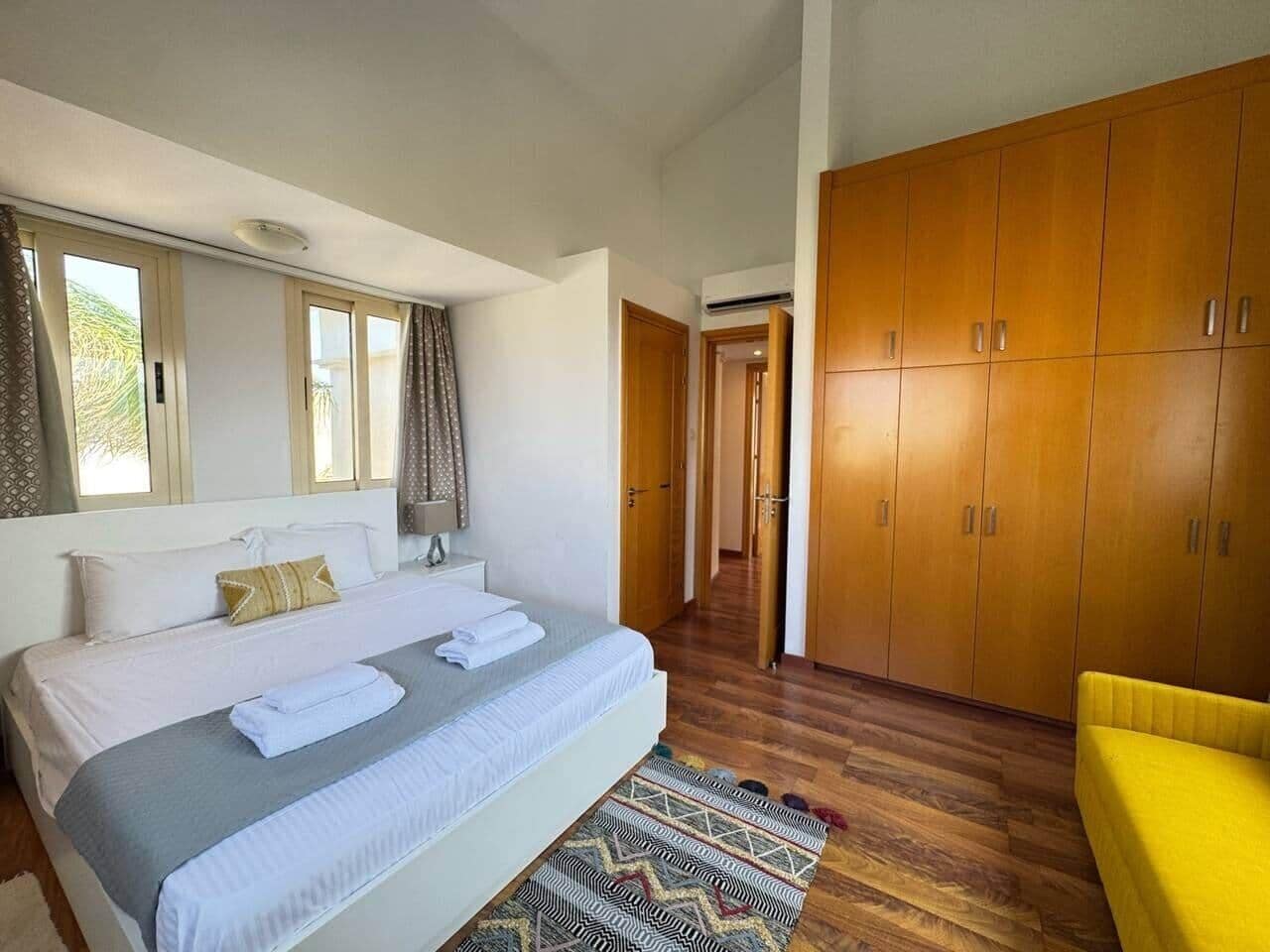 A bedroom with a bed, a wardrobe, a mirror, and a window.