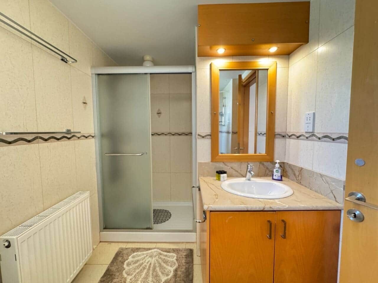 Un baño con ducha, lavamanos y espejo.