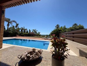 A clear blue pool with lounge chairs and a potted plant on a patio. - Emerald Seafront Residence (Sotira)