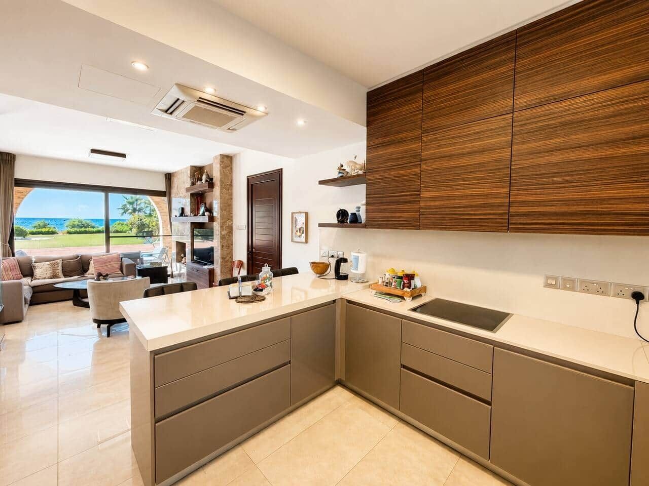Une cuisine moderne dotée d’un grand îlot central, de meubles de rangement intégrés et offrant une vue sur l’extérieur.