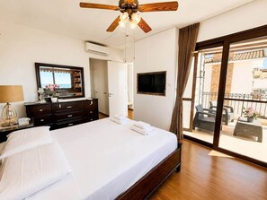 Ein Hotelzimmer mit Bett, Schminktisch, Fernseher und einem Balkon mit Gartenmöbeln.