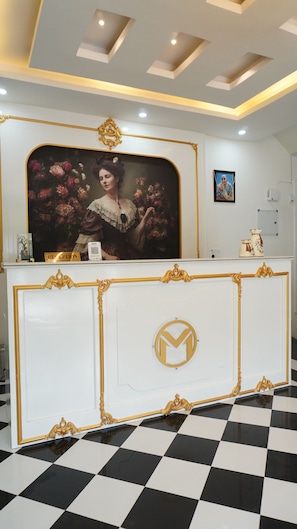 A reception desk with a large mirror, a framed portrait, and a checkered floor. - Macpro Inn Rubystone Express  (Dehradun)