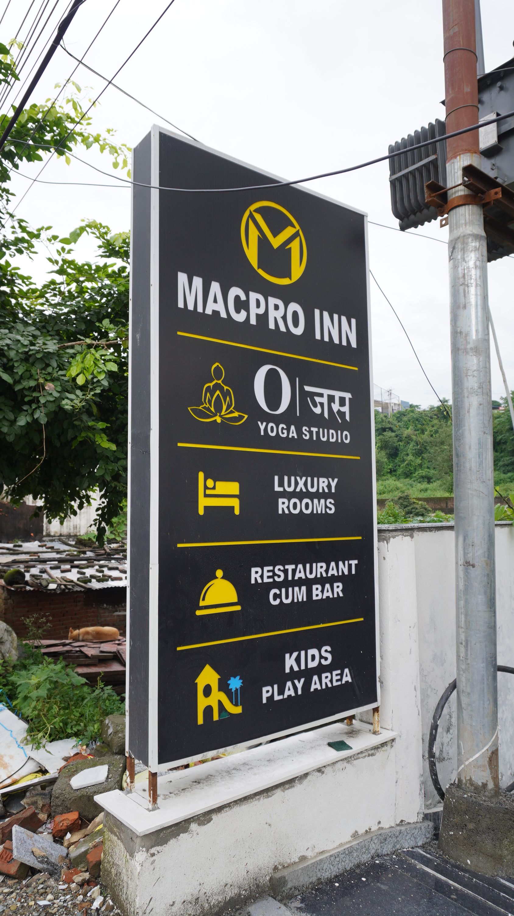 Señal de MACPRO INN con servicios que incluyen un estudio de yoga, habitaciones de lujo, un restaurante y bar, y una zona de juegos para niños.
