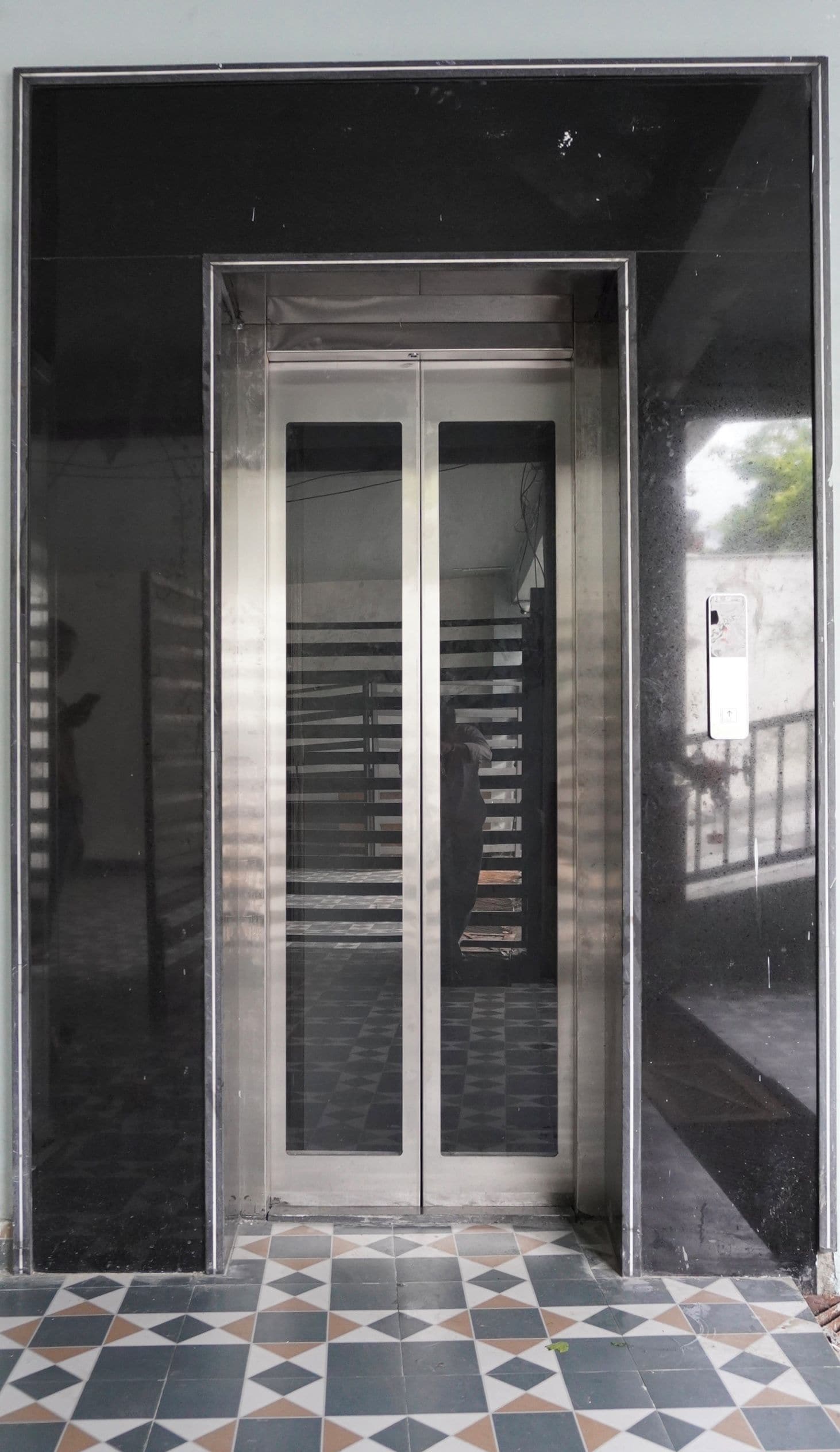 A double door with a metal frame and glass panels, leading to an interior space with a tiled floor.