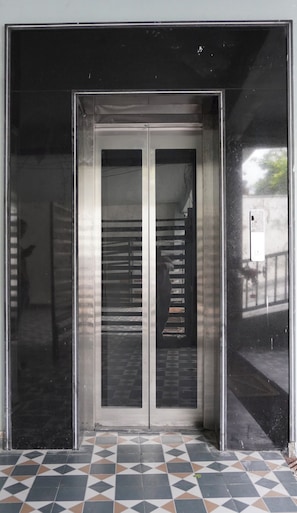 A double door with a metal frame and glass panels, leading to an interior space with a tiled floor. - Macpro Inn Rubystone Express  (Dehradun)