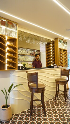 A bar area with a counter, bar stools, and shelves with glassware. - Macpro Inn Rubystone Express  (Dehradun)