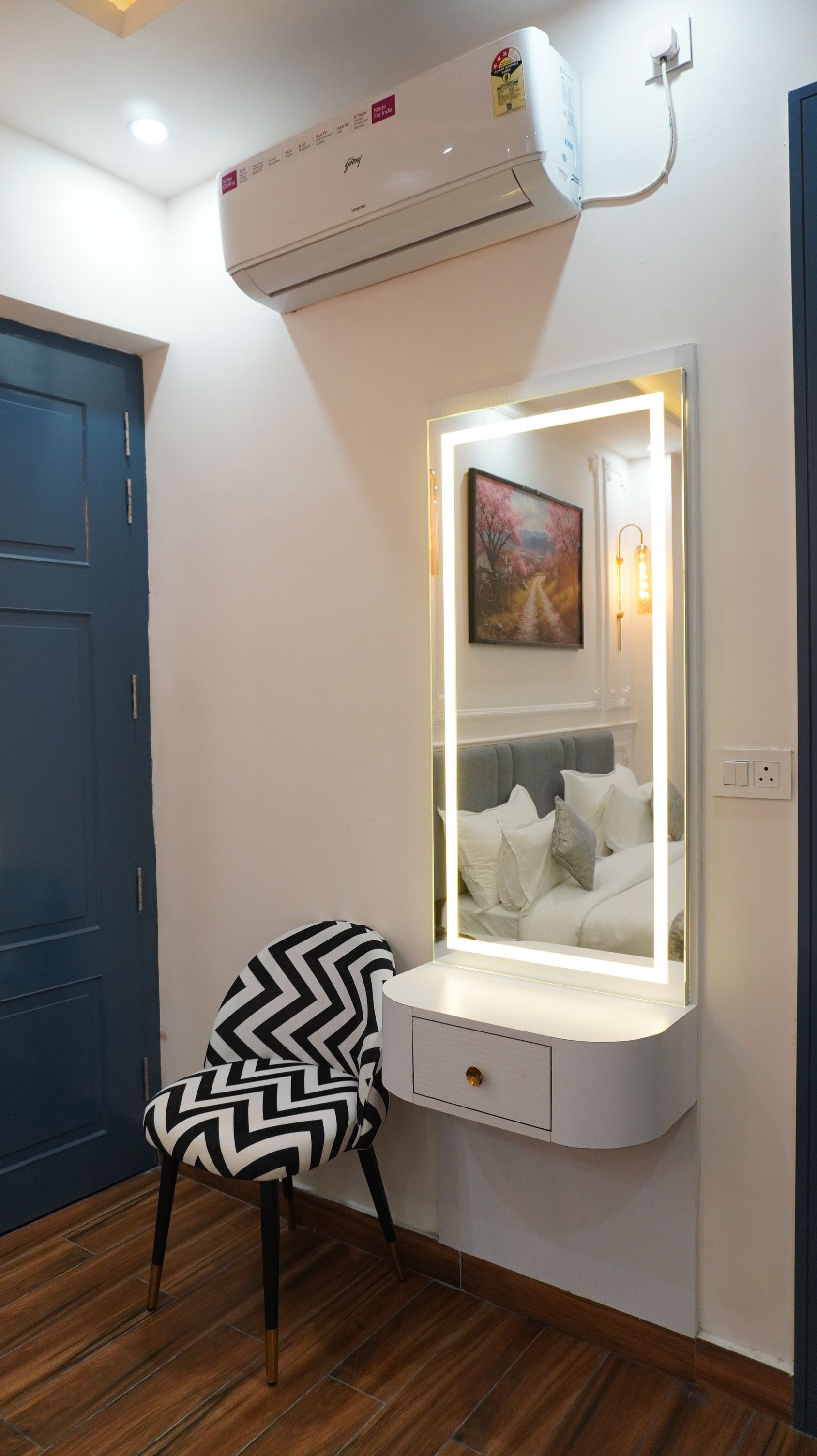 A vanity with a mirror, a chair, and an air conditioning unit mounted on the wall.