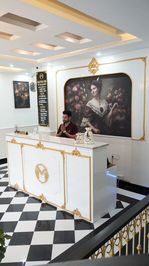 Una mesa de recepción con mostrador de registro, un reloj y un retrato enmarcado en la pared.
