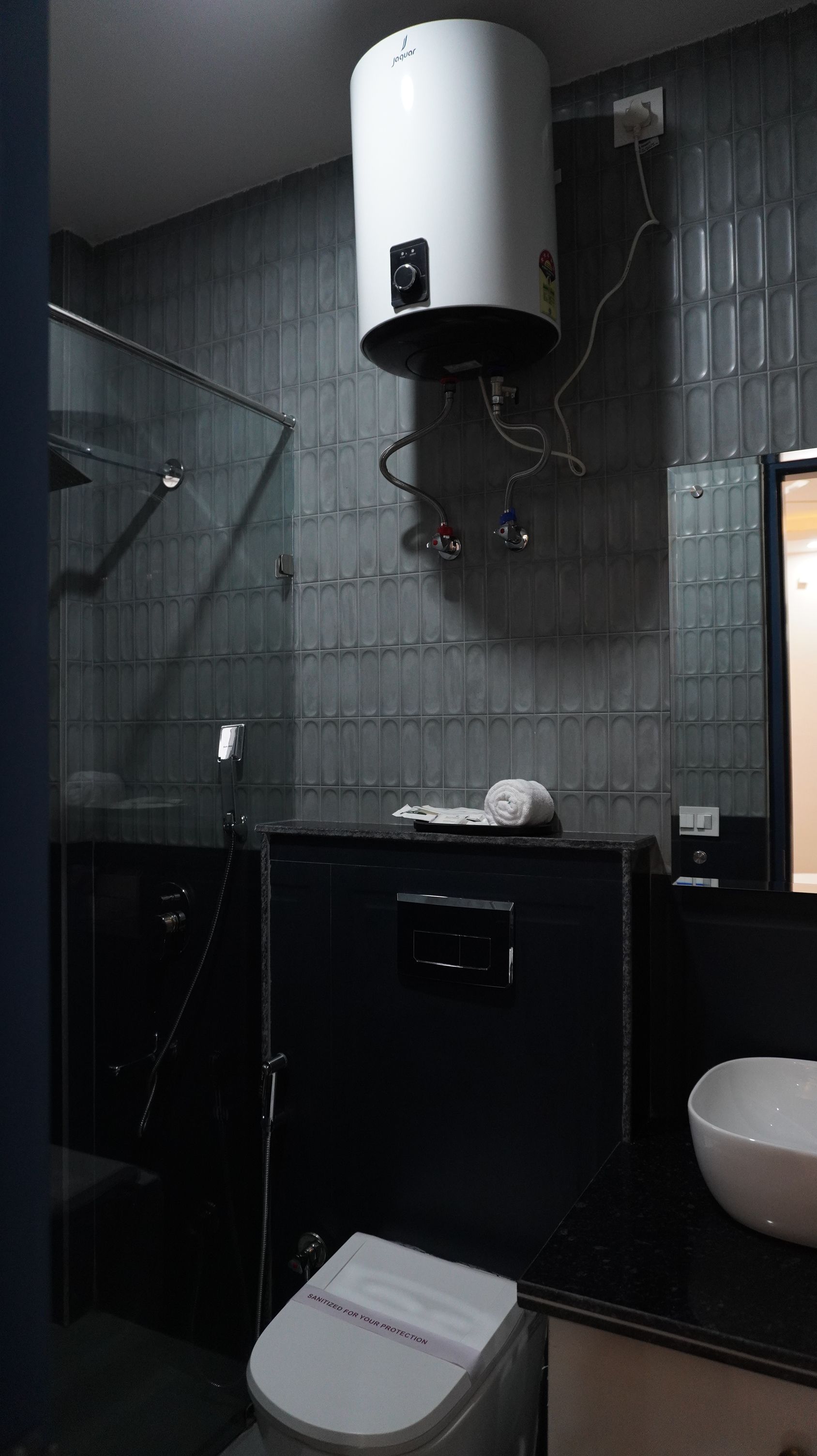 A bathroom with a toilet, a sink, a mirror, a towel, and a shower.