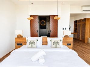 A hotel room with a large bed, wooden headboard, two bedside lamps, a wooden wardrobe, and a ceiling fan. - Villa Elora - Bingin Pecatu (Pecatu)