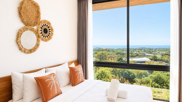Ein Hotelzimmer mit großem Fenster und Blick auf eine grüne Landschaft und das Meer.