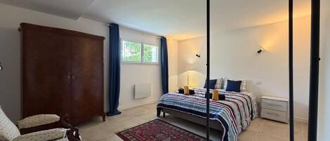 Un dormitorio con cama, una silla, un armario y una ventana.