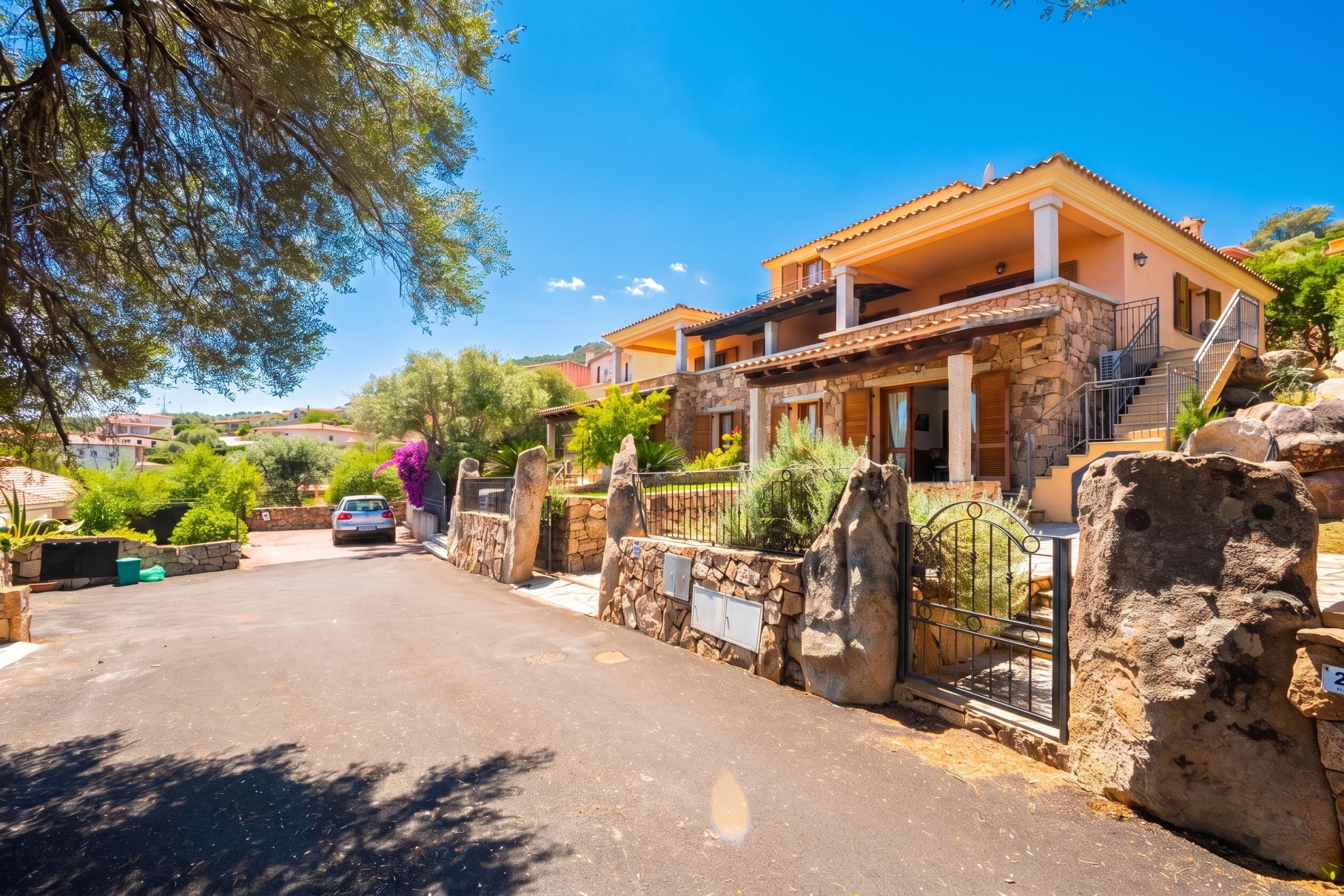 A two-story house with a stone facade, a balcony, and a gated driveway.