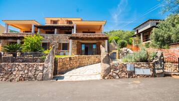 A two-story house with a stone facade, a balcony, and a paved entrance.