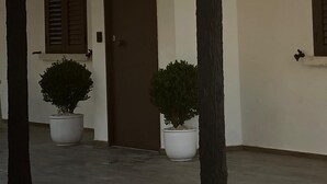 Un edificio con fachada blanca, puerta marrón y dos macetas.