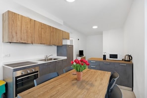 A modern kitchen with wooden cabinets, a built-in oven, and a dining table with chairs.