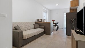 Een knus woongedeelte met een bank, een kitchenette en een eettafel.