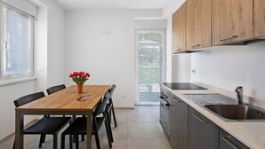 Een moderne keuken met een houten eettafel, zwarte stoelen en uitzicht op een balkon.