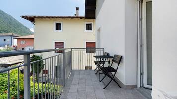 A balcony with a table and chairs, a metal railing, and a door.