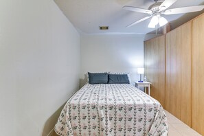 A bedroom with a bed, a ceiling fan, a nightstand, and a wooden wardrobe. - Inviting Unit, 10 Mi to Airport & Vintage Park! (Houston)