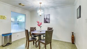 Een eetruimte met een kroonluchter, een tafel met stoelen, een vaas met bloemen en een afbeelding van de Eiffeltoren aan de muur.