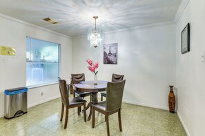 Ein Essbereich mit einer Chandelier, einem Tisch mit Stühlen, einer Vase mit Blumen und einem Bild des Eiffelturms an der Wand.