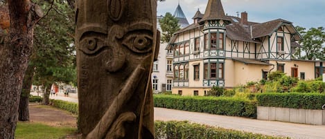 A historic building with a prominent tower and a large tree with a carved face in the foreground.