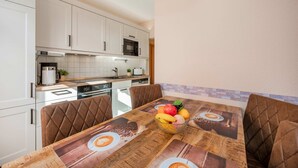 A modern kitchen with white cabinets, a microwave, and a dining table with a fruit bowl. - Holtz 1 Vacation Rental with a barbecue area in the garden and a lawn for sunbathing - Dogs are (Zinnowitz)