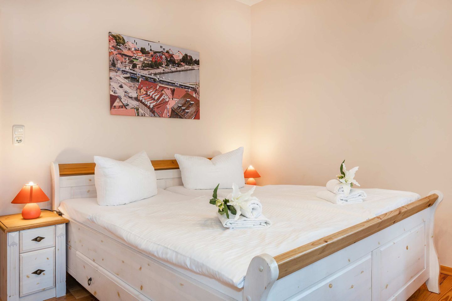 Une chambre à coucher comprenant un lit, deux tables de chevet, une commode, un tableau accroché au mur et une fenêtre.