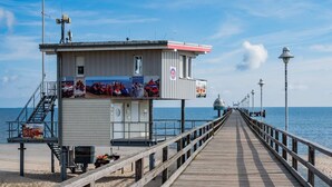 A pier with a lifeguard tower, a wooden walkway, and a clear view of the ocean. - Holtz 1 Vacation Rental with a barbecue area in the garden and a lawn for sunbathing - Dogs are (Zinnowitz)