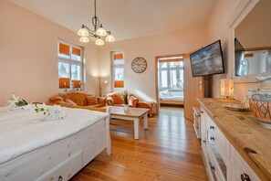 Ein Hotelzimmer mit einem Bett, zwei Sofas, einem Couchtisch, einem Fernseher und einer Wanduhr.