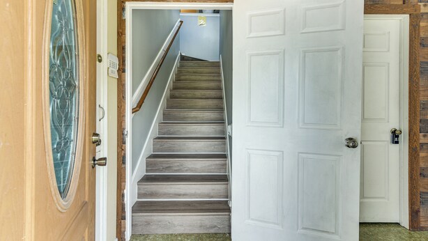 Eine Treppe führt zu einem Raum mit einer weißen Tür, Holzwänden und einem Sicherheitstastatur.