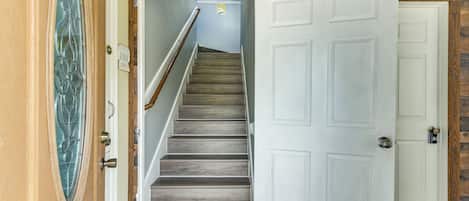A staircase leading to a room with a white door, wooden walls, and a security keypad.