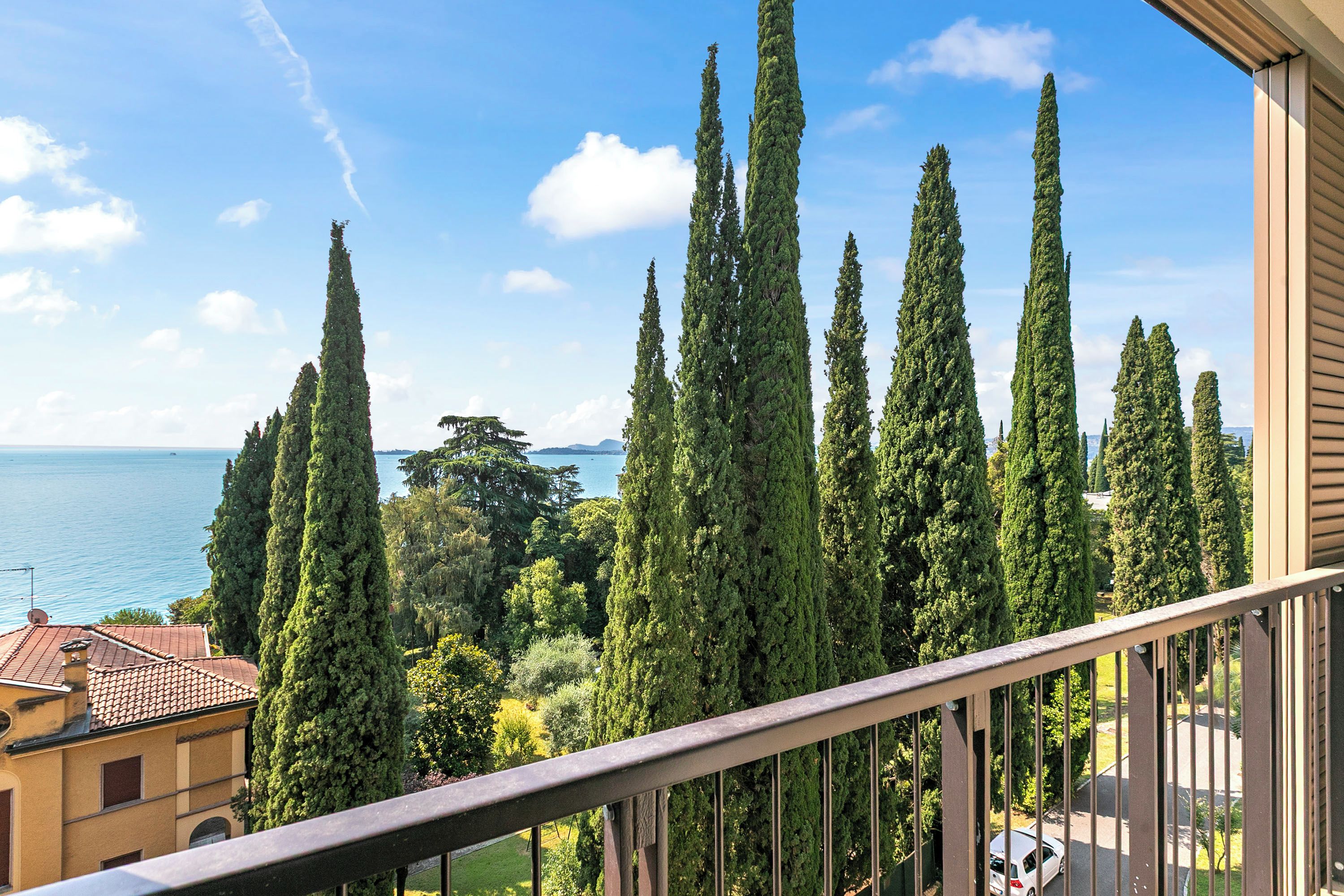 Varanda com vista para ciprestes altos e um corpo de água.