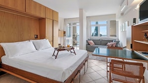 A hotel room with a large bed, a small table with a tray, a sofa, and a TV. - Hendrik Vittoriale Lake View Shared Pool (Gardone Riviera)
