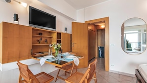 A modern kitchen with wooden cabinets, a dining table set for four, and a flat-screen TV mounted above the counter. - Hendrik Vittoriale Lake View Shared Pool (Gardone Riviera)