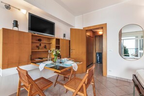 Uma cozinha moderna com armários de madeira, uma mesa de jantar posta para quatro pessoas e uma televisão de tela plana montada acima do balcão.