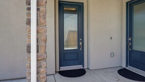 A residential entrance with a dark-colored door, a stone pillar, and a concrete driveway. - 1BR Guest House w/ Private Entrance and Laundry (Bakersfield)