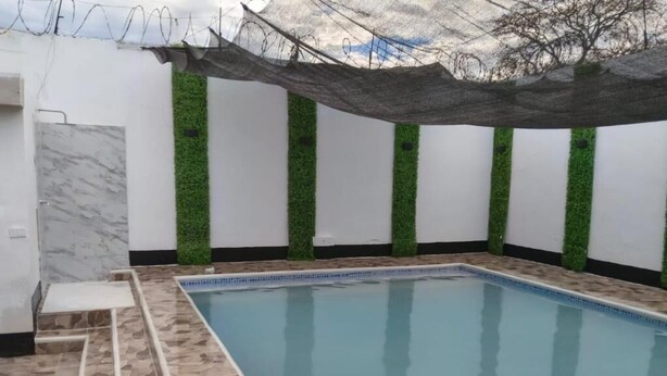 Una piscina con plataforma de baldosas, rodeada por muros con jardines verticales.